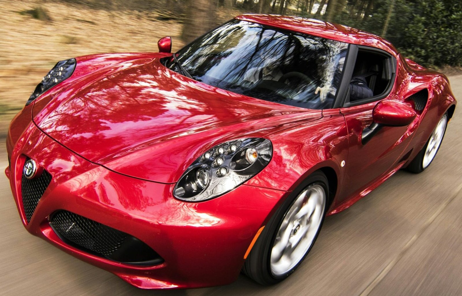 A sleek red sports car driving fast on a forest road, showcasing speed and luxury.